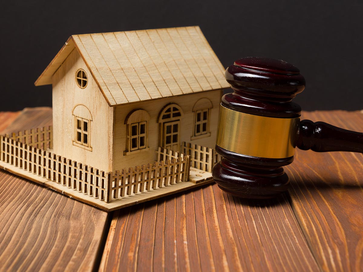 Tiny wooden house resting next to a judge’s gavel.