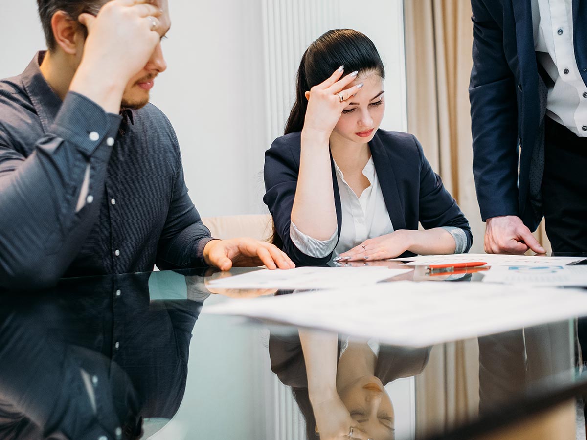 Lawyer working with two clients who are looking at legal paperwork with perplexed expressions.