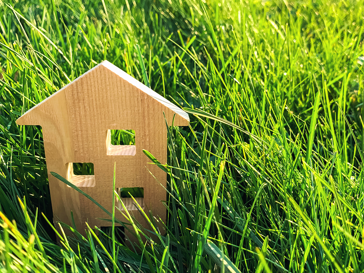 Miniature wooden house on green grass.