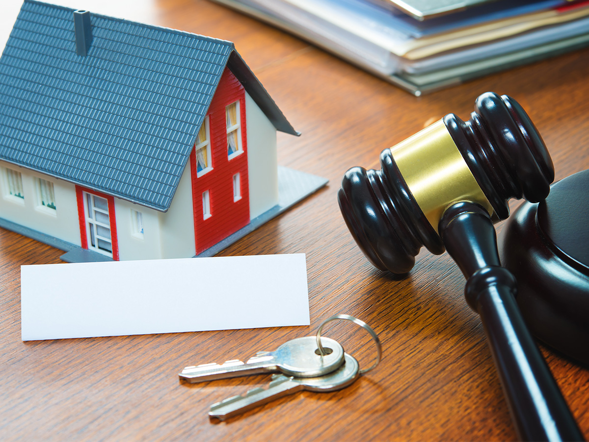 Real estate law concept, with a judge’s gavel next to a small toy house.