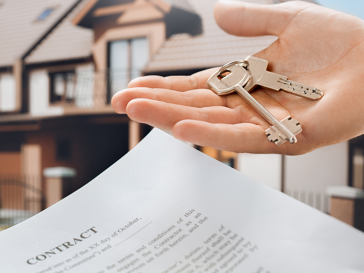 Young woman holding the keys to a real estate property with a contract in the foreground.