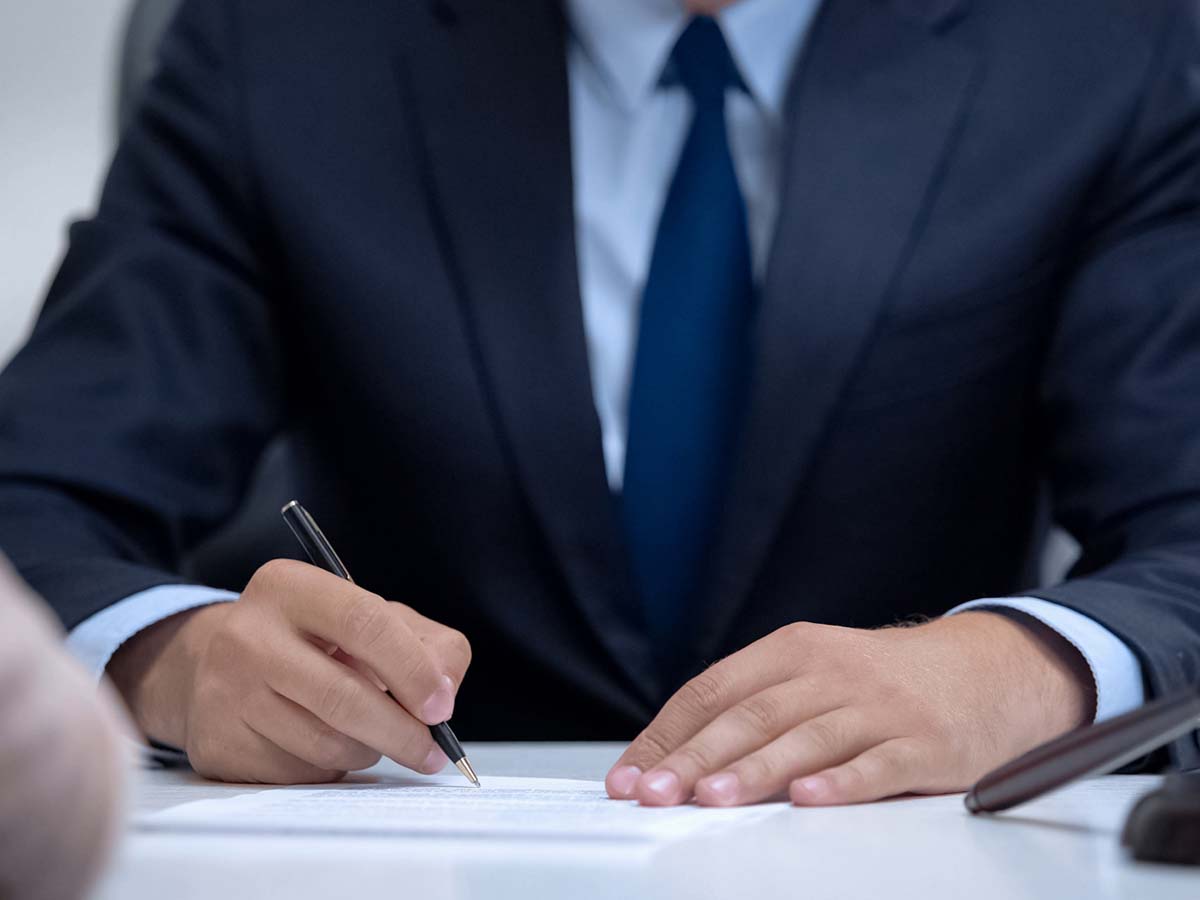 A man signing a legal document on a desk