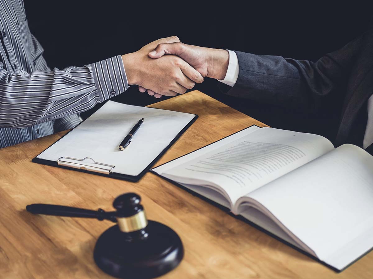 A lawyer and a client shaking hands at a desk