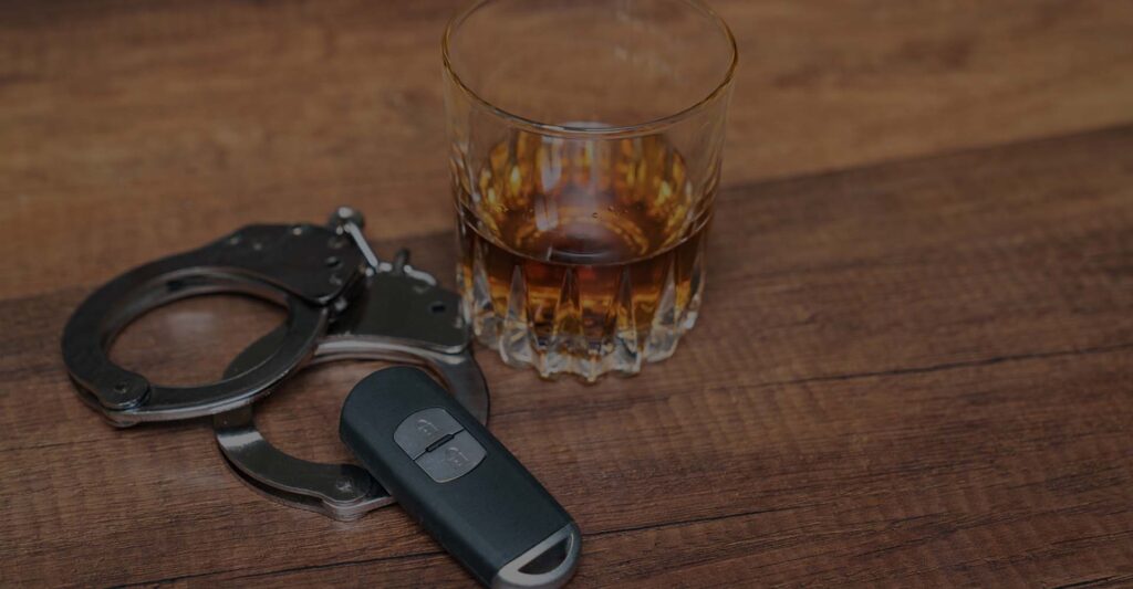 A pair of handcuffs next to an alcoholic drink and a key fob
