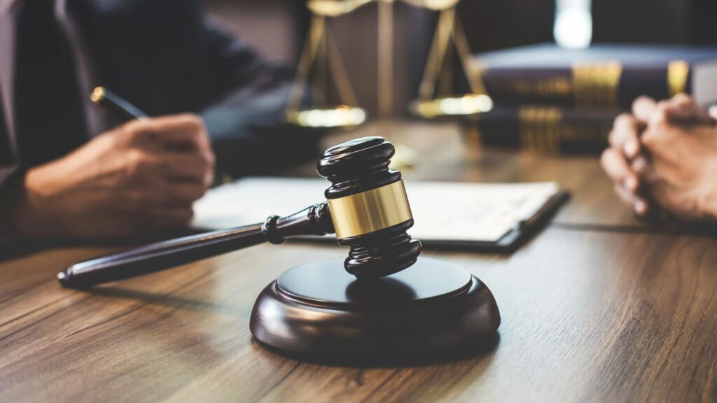 Two people at a desk with a gavel and scales of justice