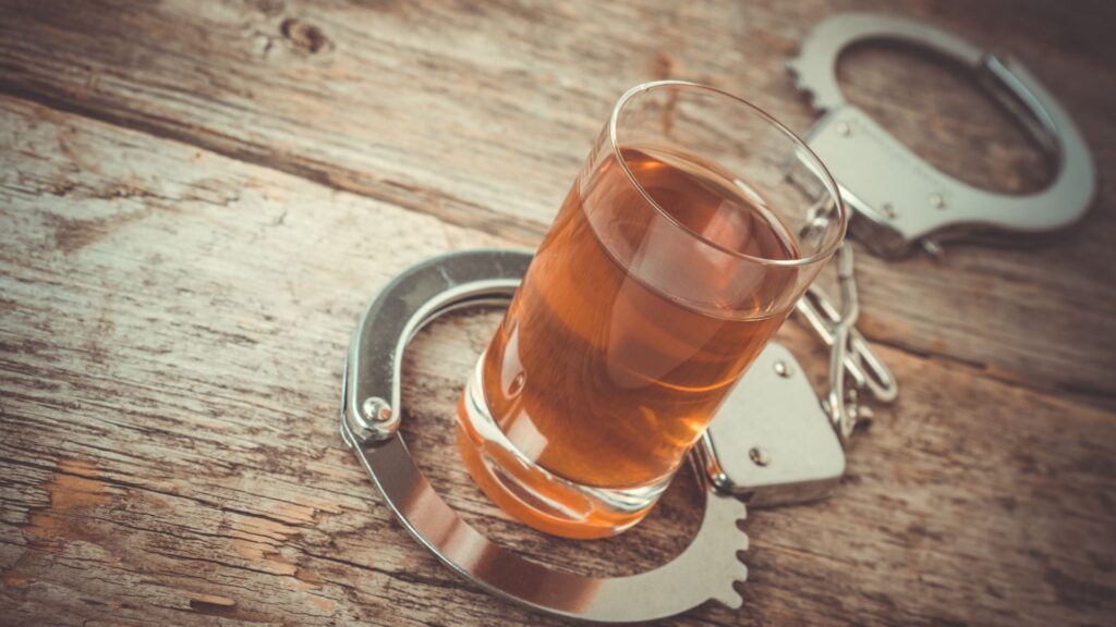 handcuffs around shot glass filled with liquor