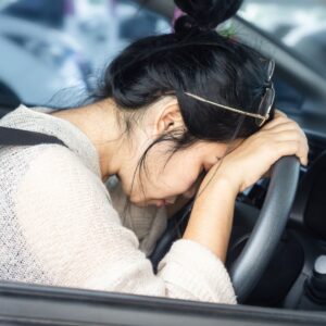 Lady with head resting on steering wheel