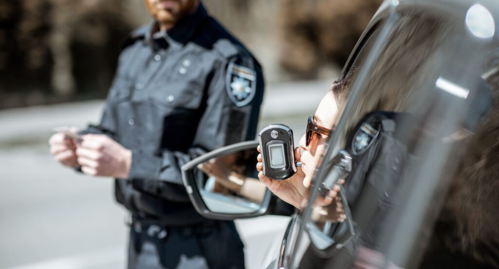 Woman doing a breathalyzer test from car