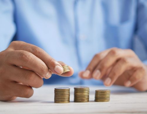 Person stacking coins to represent financial planning and support.