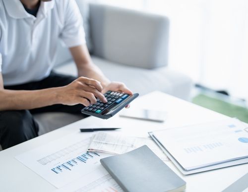 Person using a calculator to review financial charts and data.
