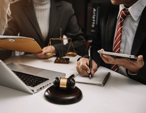 Lawyers working with a gavel, laptop, and scales.