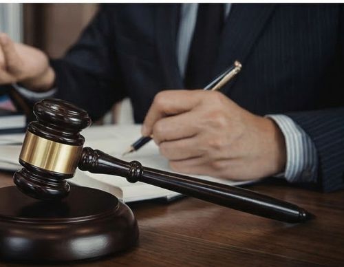 A legal professional signing documents behind a gavel.