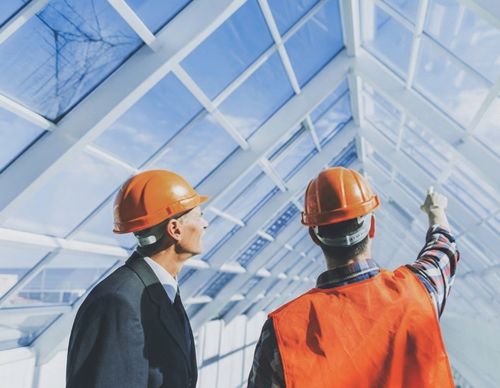 Architect and contractor inspecting a modern glass ceiling structure.