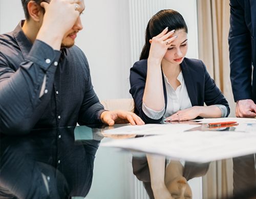 Stressed parents reviewing legal documents at a table.