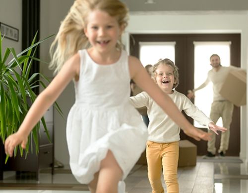 Happy children running into their new home with boxes.