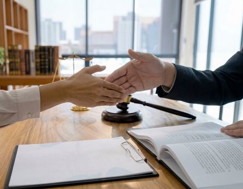 Two people reaching to shake hands in a legal office.