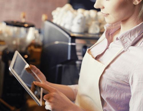 Barista in an apron using a digital tablet.