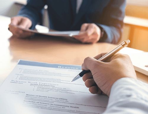 Hand with pen reviewing a professional resume