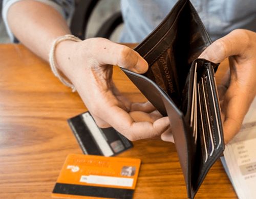 Hands holding an empty brown leather wallet.