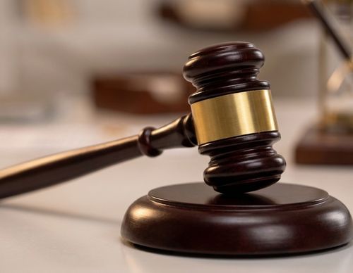 Wooden judge's gavel resting on a sound block.