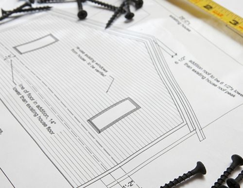 Construction blueprints surrounded by loose metal screws.