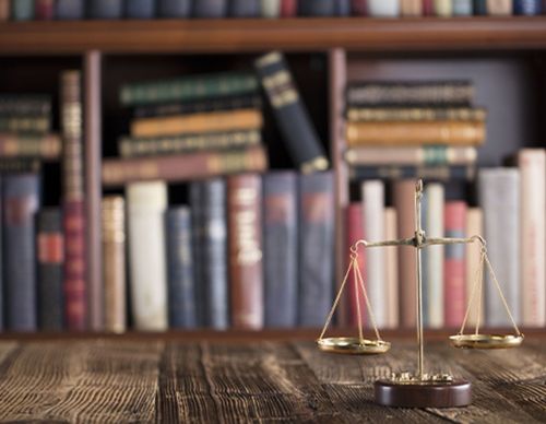 Brass scales of justice in front of law books.