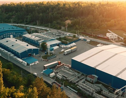 Industrial warehouse complex near a dense forest.