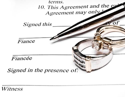Wedding rings resting on a marriage or prenup agreement.