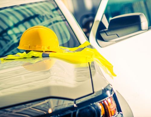 A yellow hard hat and safety vest on a car.