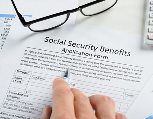 A hand filling out a Social Security benefits application.