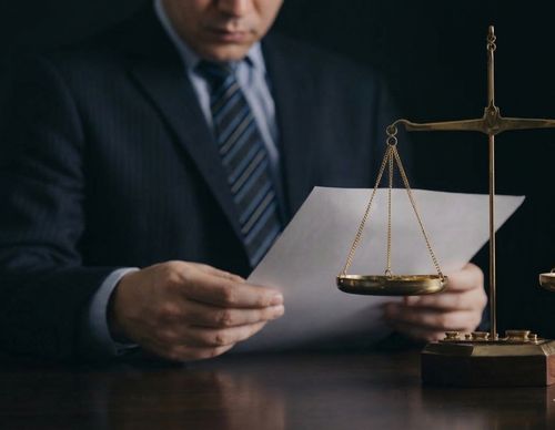 A lawyer reviewing documents next to brass scales.