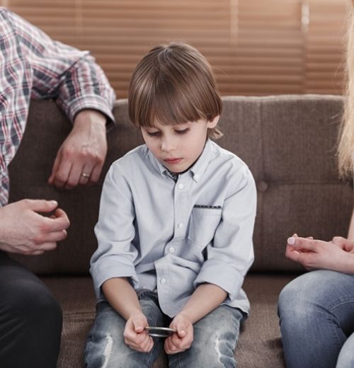 A sad young boy sitting between his parents.