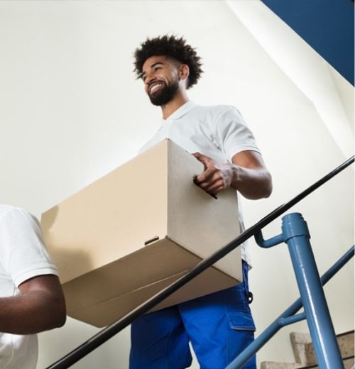 A smiling man carrying a cardboard moving box