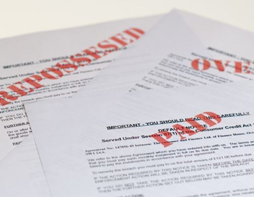 Close-up of "REPOSSESSED" and "DEFAULT NOTICE" legal papers