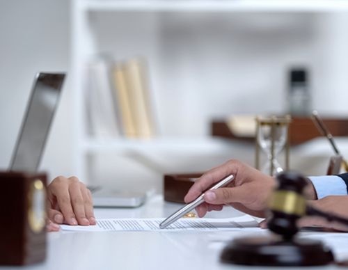 Hand pointing to a legal document next to a gavel.