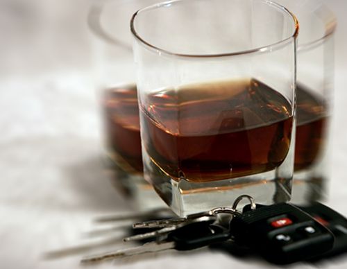 Car keys sitting in front of two glasses of whiskey.
