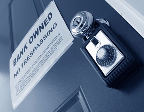 "Bank Owned" notice and lockbox on a blue door.