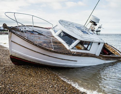 A white boat washed up on a pebble beach