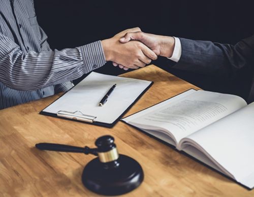 Legal handshake over a gavel and open law book.