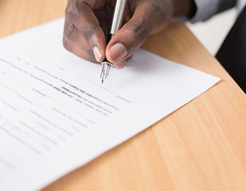 Close-up of a hand signing a document with a pen