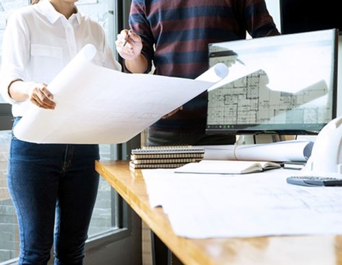 Professionals reviewing a large printed architectural blueprint