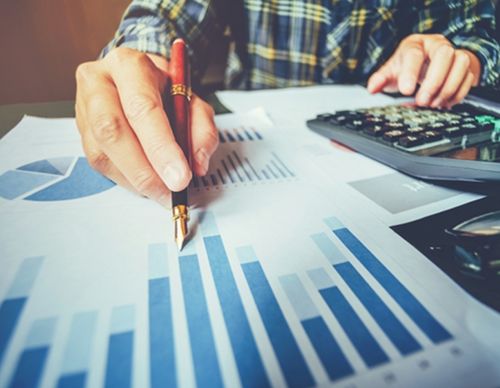 Person using a fountain pen to analyze bar charts.