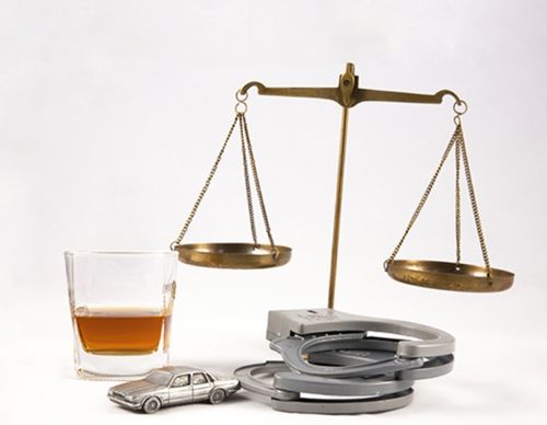 Handcuffs, whiskey, and a toy car under brass scales
