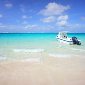 A small motorboat anchored on a clear white-sand beach, representing coastal property rights and waterfront legal services.